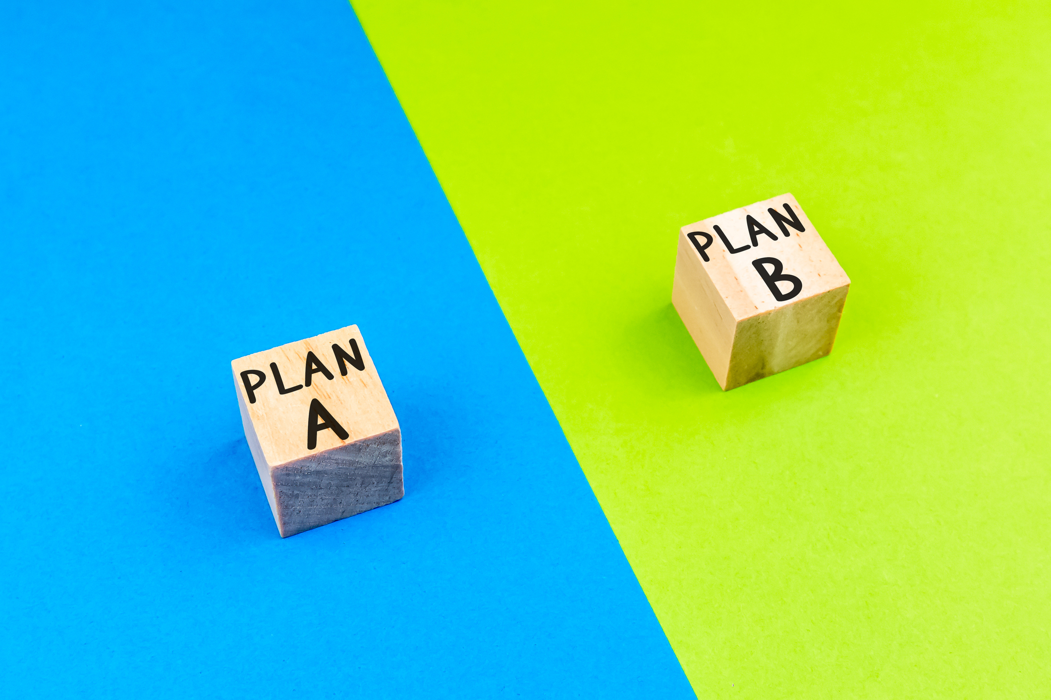 wooden block with word PLAN A and PLAN B. in front of a color-divided background