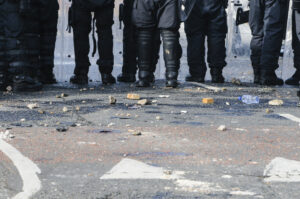 Stones and bricks litter the road as police riot squad move forward toward civil unrest