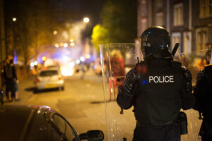 Riot police move forward towards burning waste bins and rioting from protests.