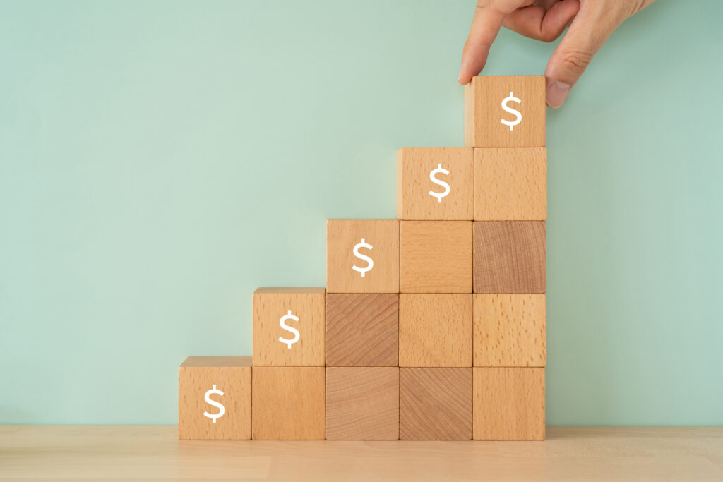 Wooden blocks with dollar signs and a human hand to represent rising claims costs