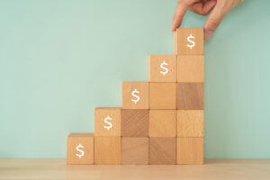 Wooden blocks with dollar signs and a human hand to represent rising claims costs