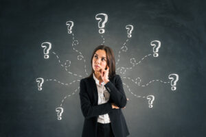 Portrait of thoughtful young businesswoman with drawn question marks. Ask and challenge concept