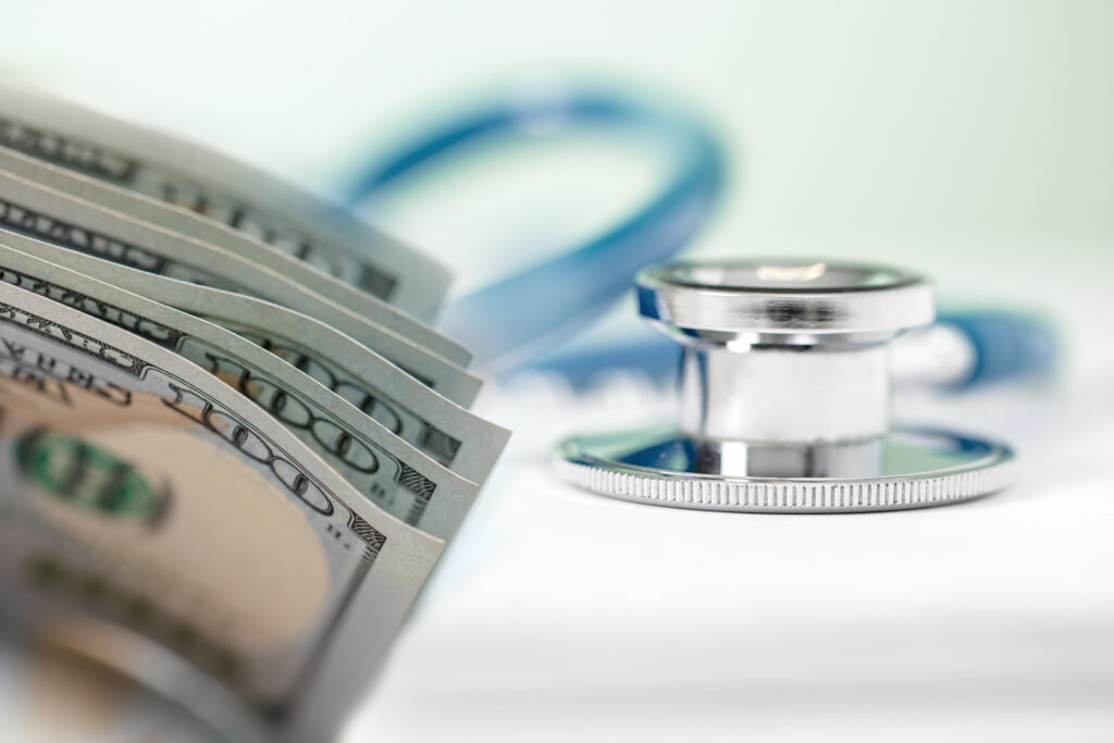 Close-up of US $100 dollars bills with a stethoscope. Shallow depth of field, space for copy.