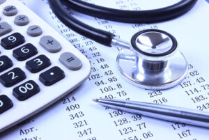 fee schedules paperwork with scheduled costs with stethoscope, calculator, and pen laid on top